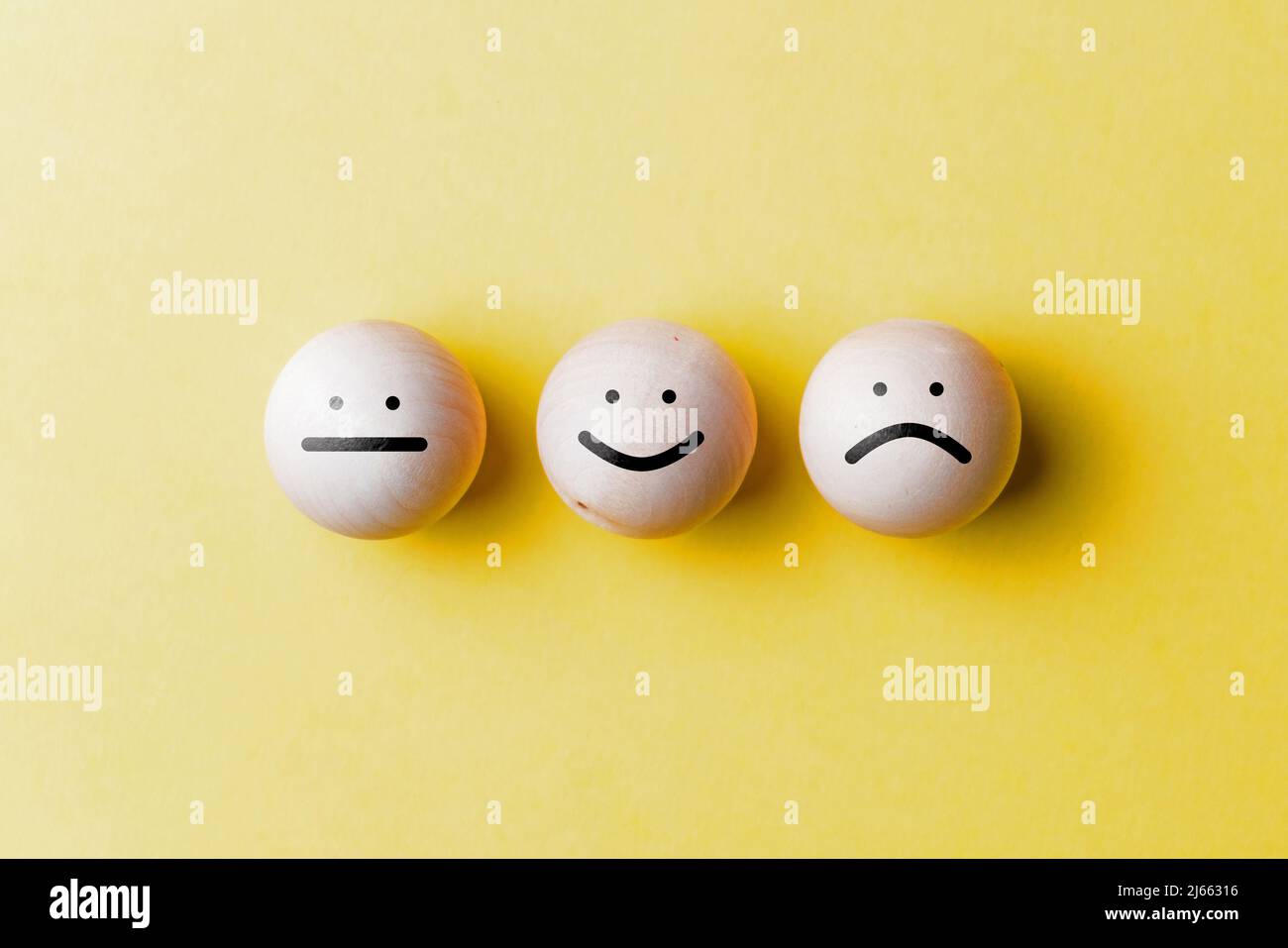 Concetto di umore buono, triste e neutro. Palline di legno con emoticon Foto Stock