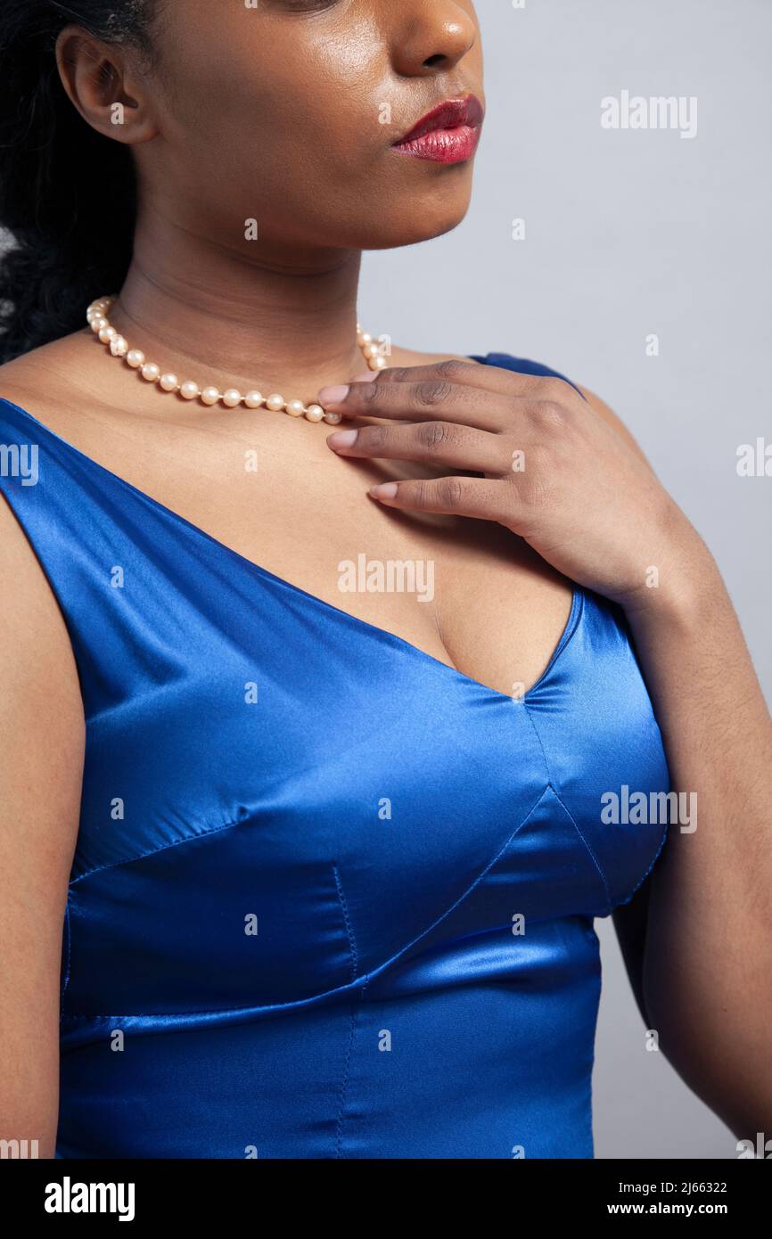 Donna con perle in abito satinato blu Foto Stock