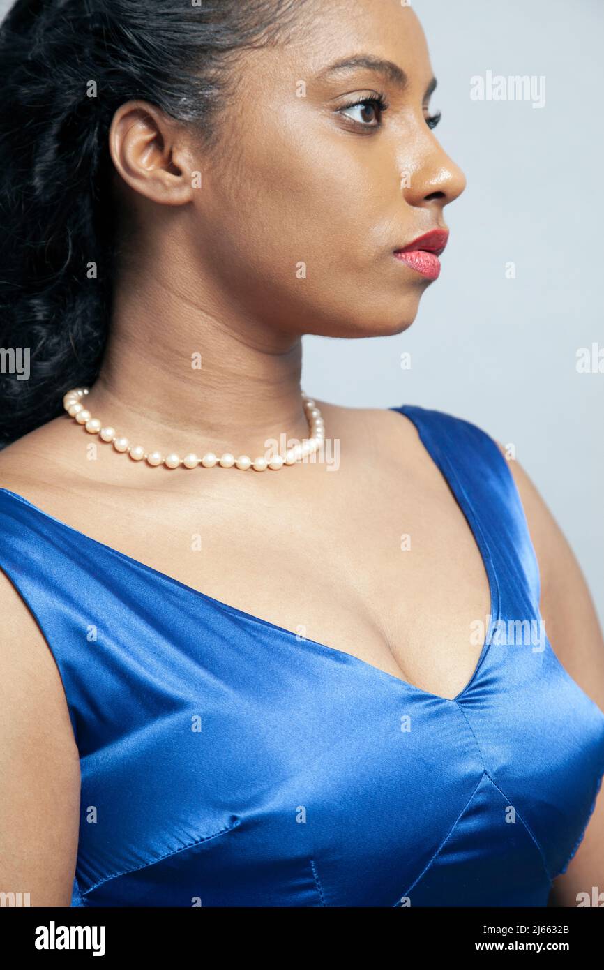 Donna con perle in abito satinato blu Foto Stock
