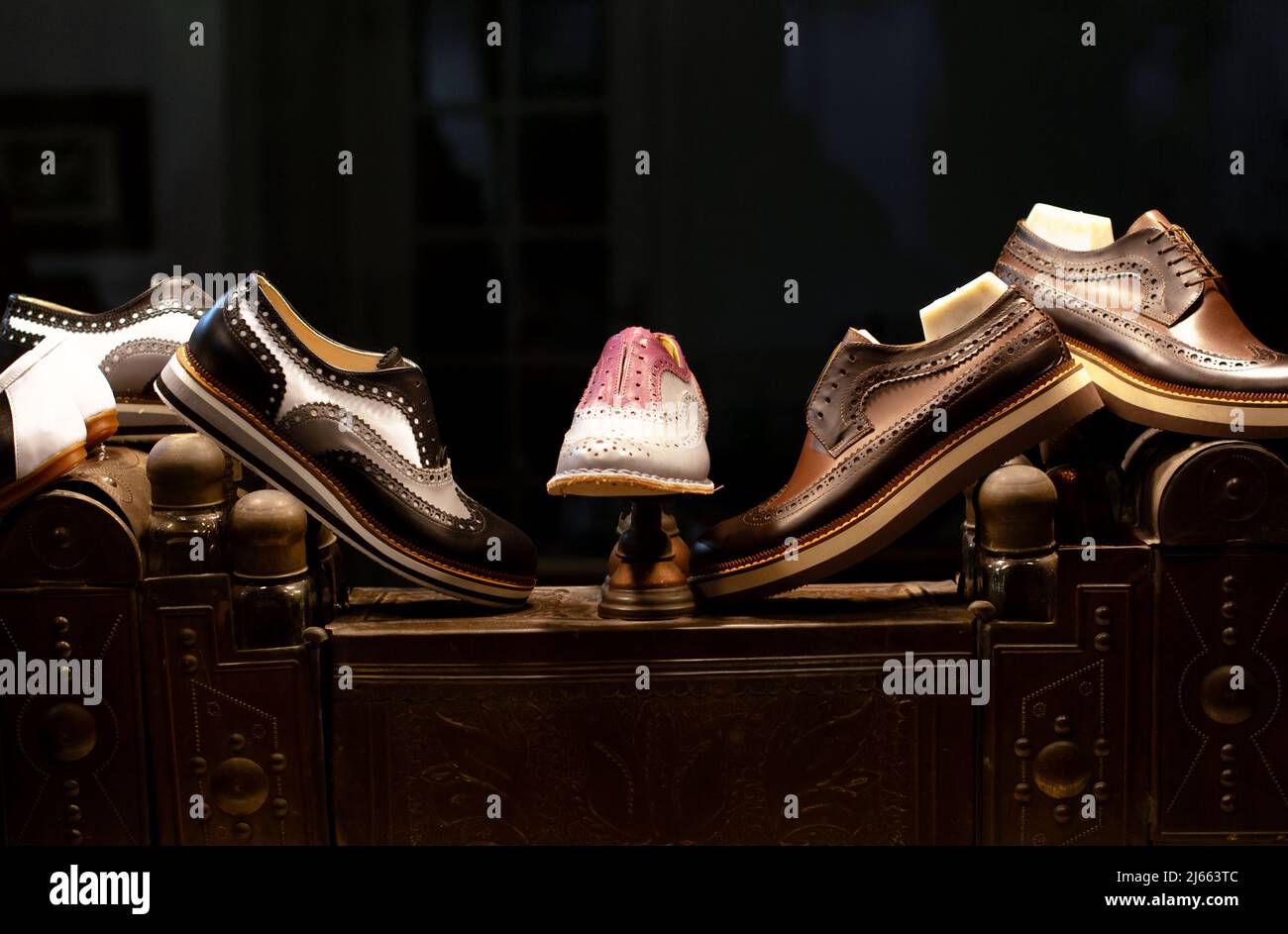 Scarpe con suole in gomma in un deposito di un laboratorio calzolaio, in piedi su un'antica scatola per la cura delle scarpe. Foto Stock