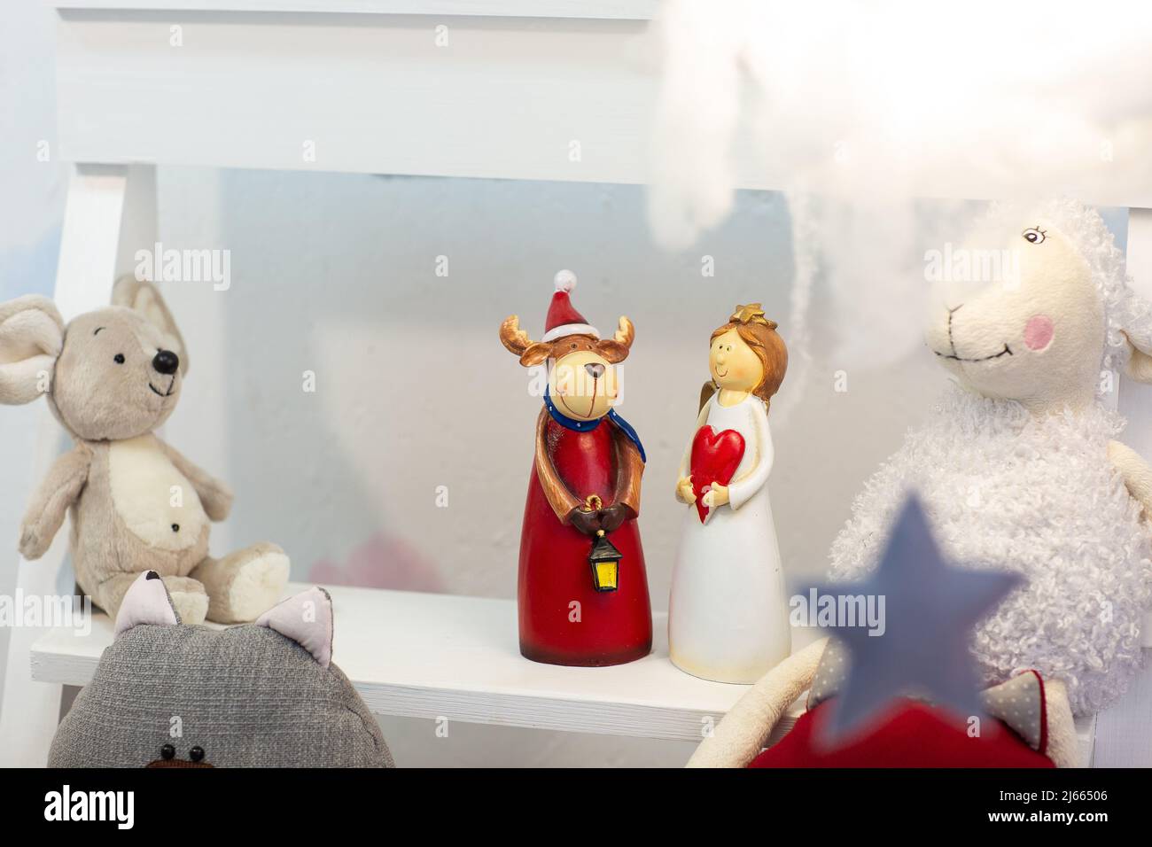 Capriolo e angelo in ceramica di Natale in abiti da festa su slitta di legno tra neve, sfondo sfocato Foto Stock