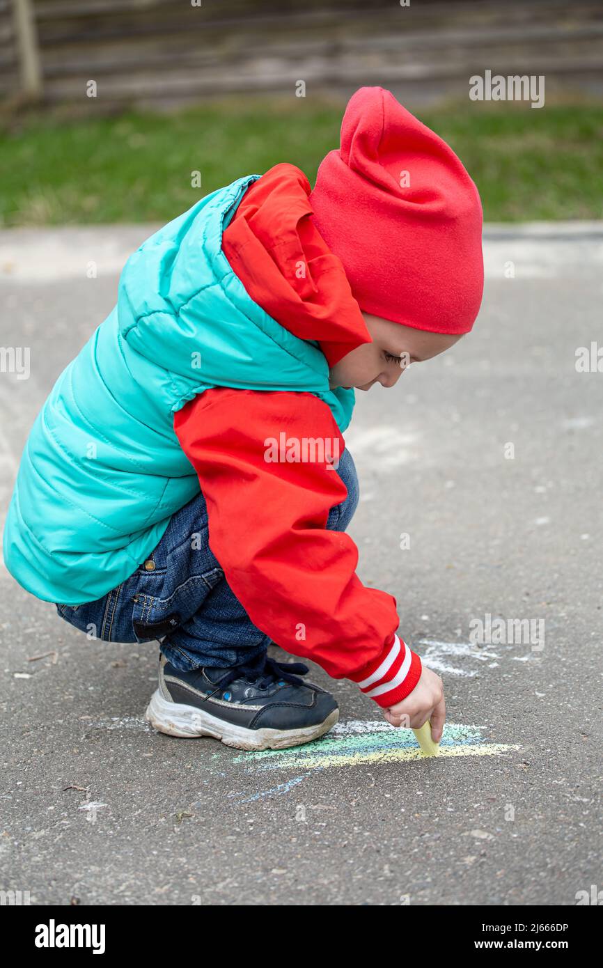 Una bambina disegna con gesso sull'asfalto Foto Stock