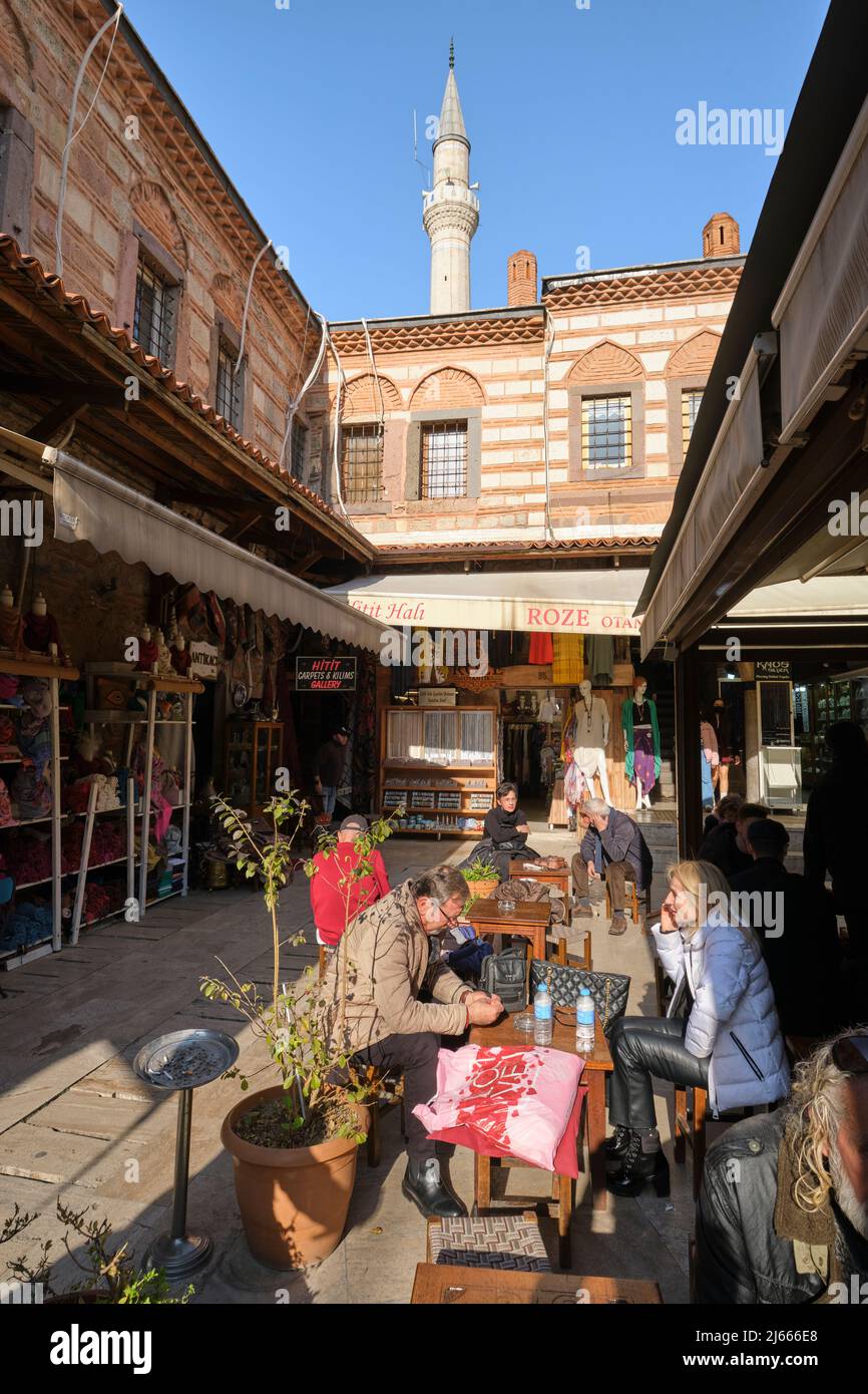La gente mangia e si rilassa con un minareto moschea sullo sfondo. Nella zona di Kemeraltı Çarşısı di Izmir, Turchia. Foto Stock