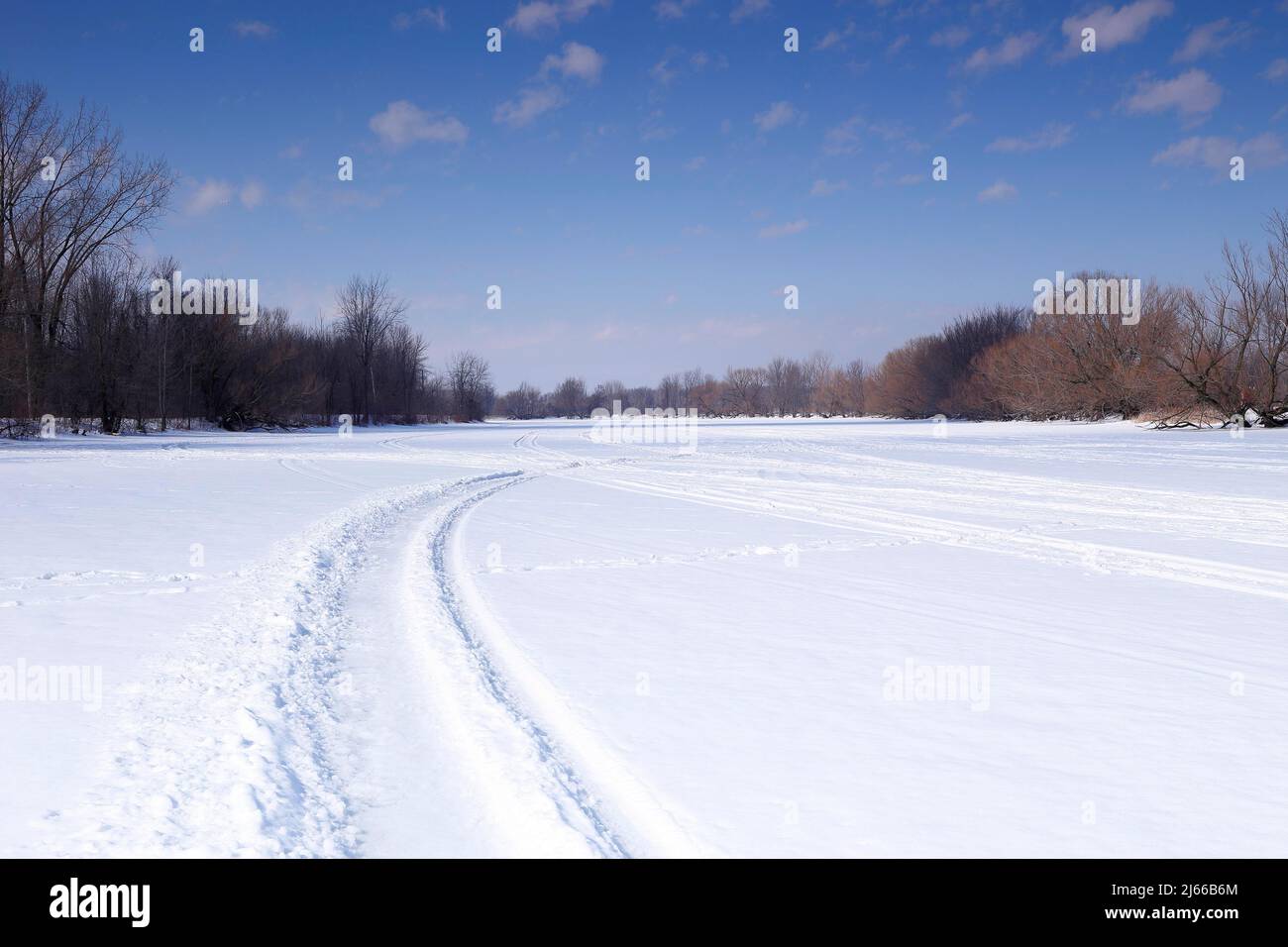 Piste per veicoli da neve su una superficie ghiacciata del fiume, Chateauguay River, provincia del Quebec, Canada Foto Stock