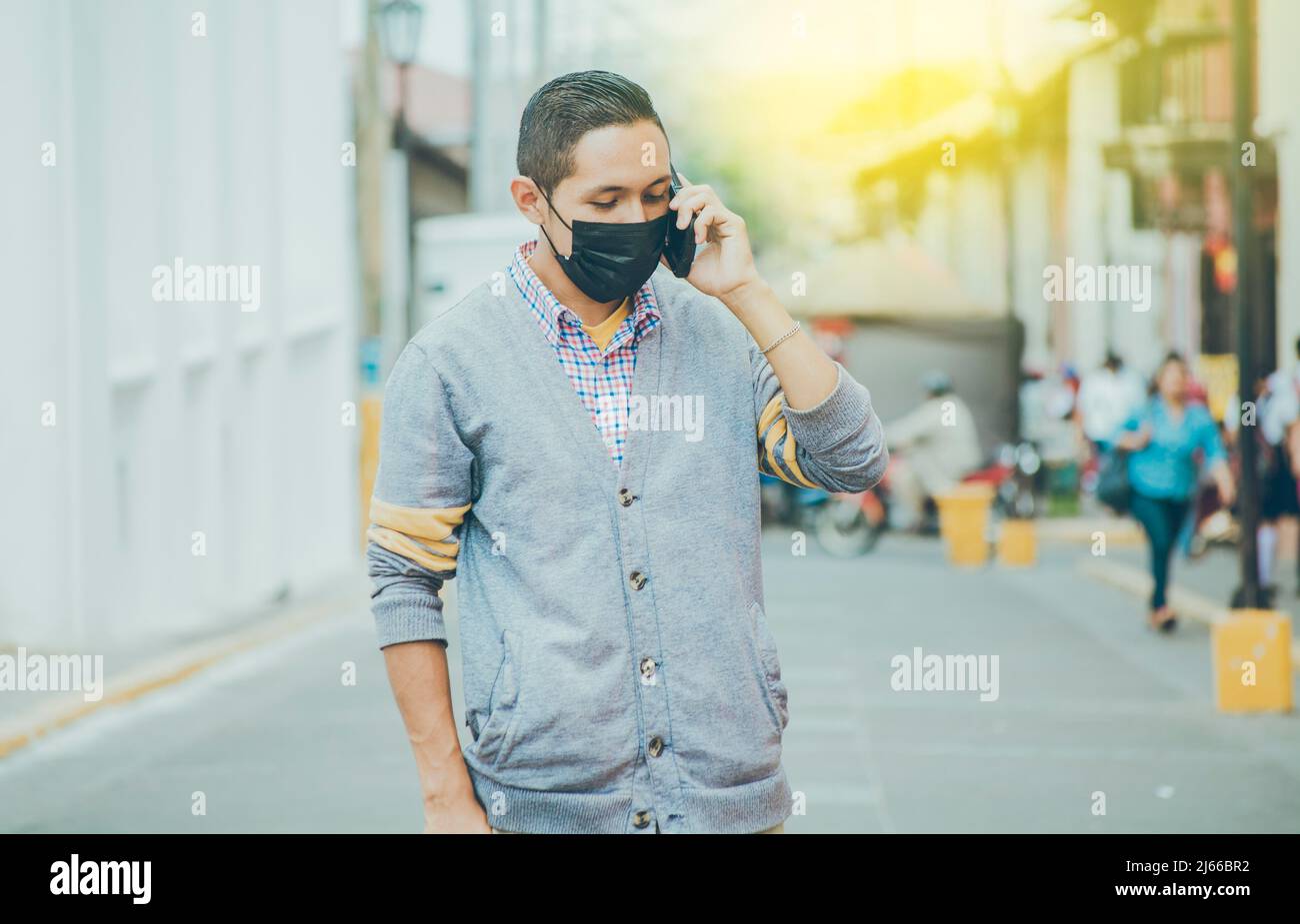 Uomo con maschera chirurgica che chiama al telefono, uomo latino con maschera che chiama al telefono in strada, uomo in maschera che chiama al telefono in strada Foto Stock