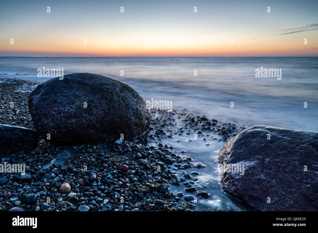 Langzeitbelichtung von grossen Felsbrocken am steinigen Strand der Ostsee bei Sonnenuntergang, Ostseebad Nienhagen, Mecklenburg-Vorpommern Foto Stock