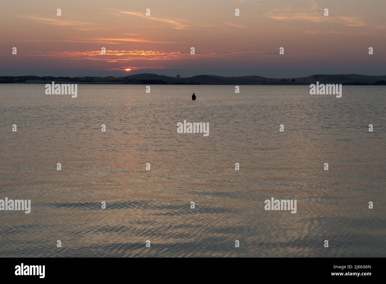 Un pescatore solista vita in profondità nelle acque del lago Pentwater al tramonto a Pentwater, Michigan Stati Uniti. Foto Stock