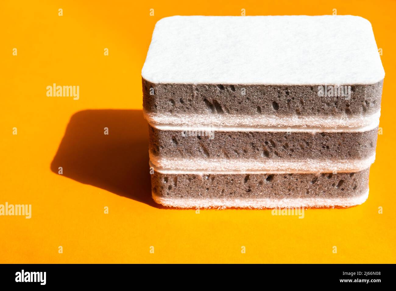 Tre spugne da cucina grigie su sfondo arancione Foto Stock