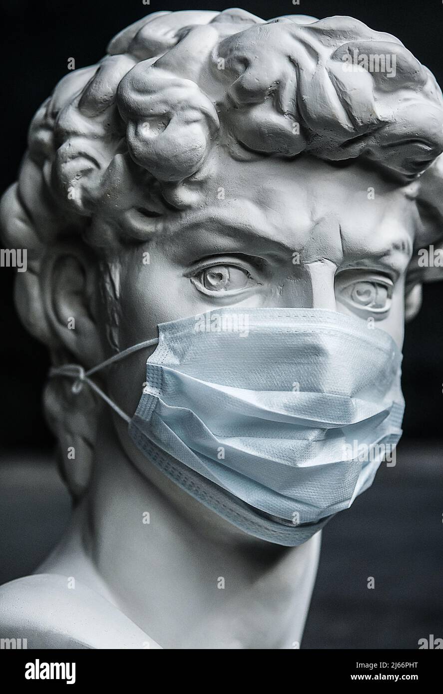 Scultura in gesso in una maschera medica. Concetto di inquinamento atmosferico, epidemie di polmonite, epidemie di Coronavirus e rischio di contaminazione biologica. Foto Stock