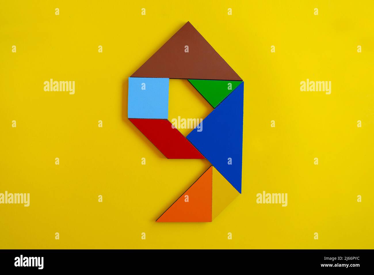 Colorato numero 9 fatto con tangram giocattolo, tangram colorato numero sette isolato su sfondo giallo, vista laterale del settimo numerico, idea di gioco per bambini Foto Stock