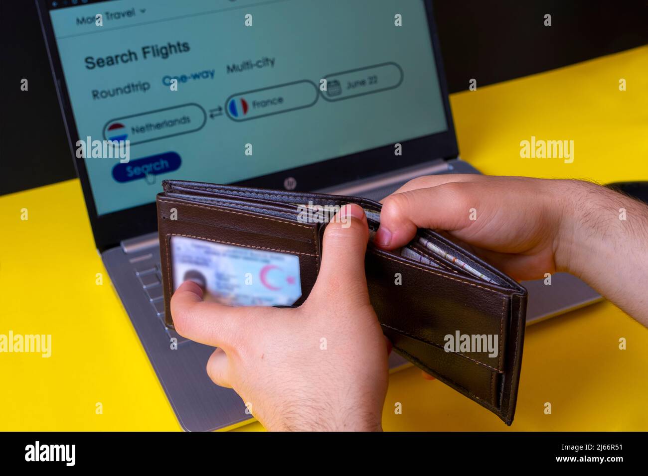 Portafoglio a mano uomo con biglietto aereo in background, destinazione tra Paesi Bassi e Francia, prenotazione biglietto per le vacanze estive Foto Stock