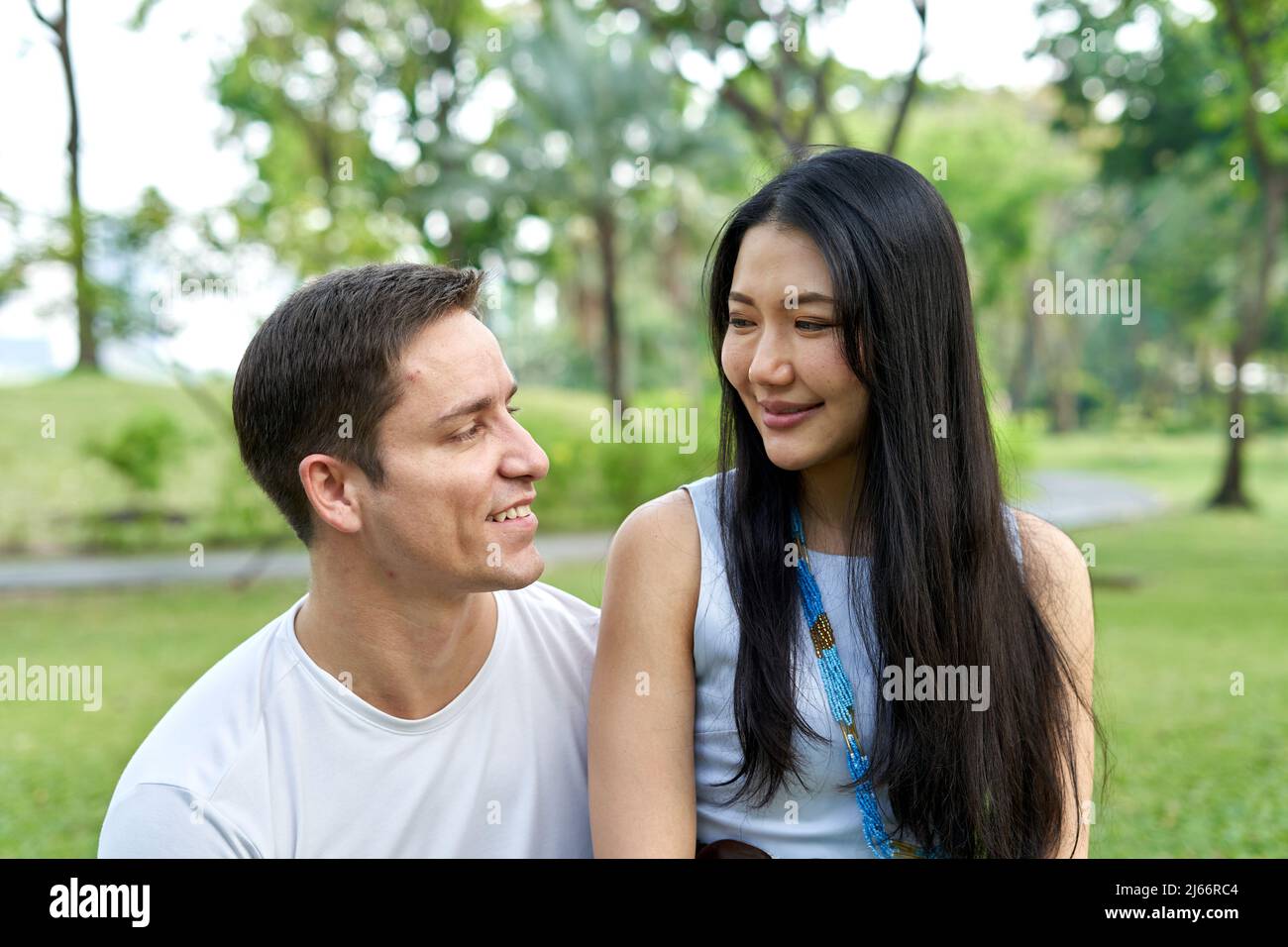 Primo piano ritratto di una coppia multietnica sorridendo insieme in un parco Foto Stock