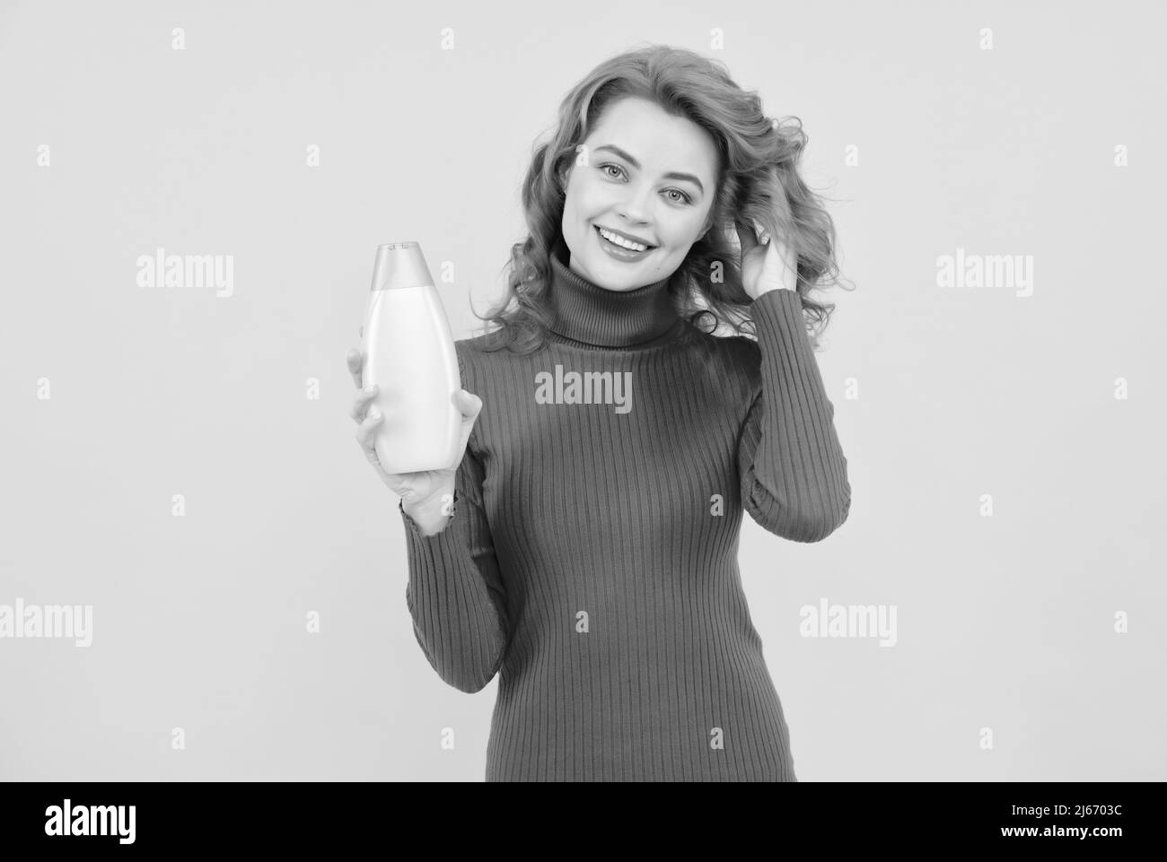 Bella donna con shampoo organico su sfondo giallo chiaro, Foto Stock