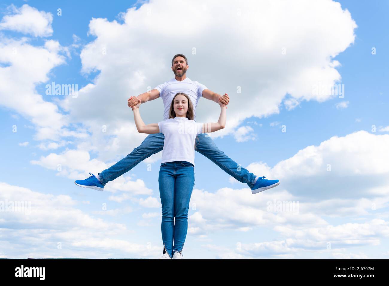 felice padre e figlia che saltano nel cielo Foto Stock