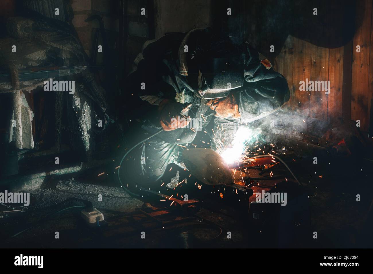 la saldatrice operatrice realizza un giunto di giunzione su un tubo mentre lavora in un'officina Foto Stock