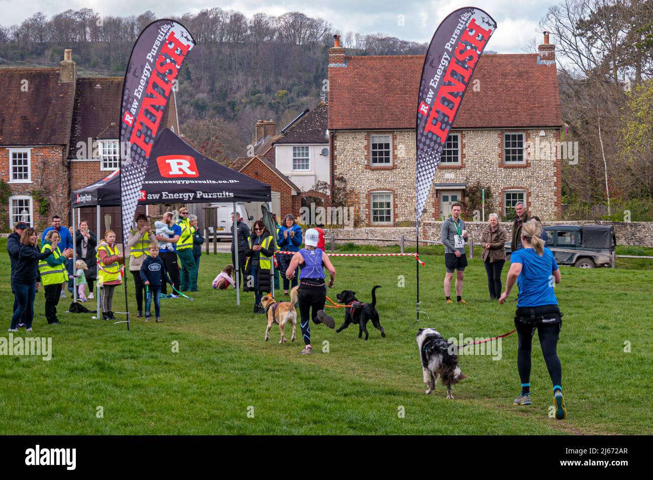 Canicross (correndo con i cani) concorrenti che partecipano alla Findon Grand National 10k Charity Run - Findon, West Sussex, Inghilterra, Regno Unito. Foto Stock