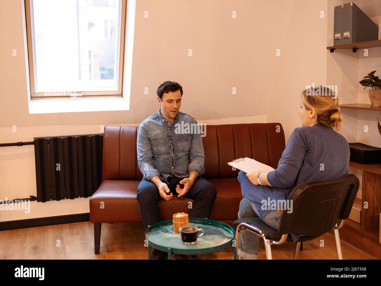 Psicoterapia. Bell'uomo serio e piacevole che visita uno psicologo e che ha una sessione psicologica mentre si occupano di problemi nei rapporti Foto Stock
