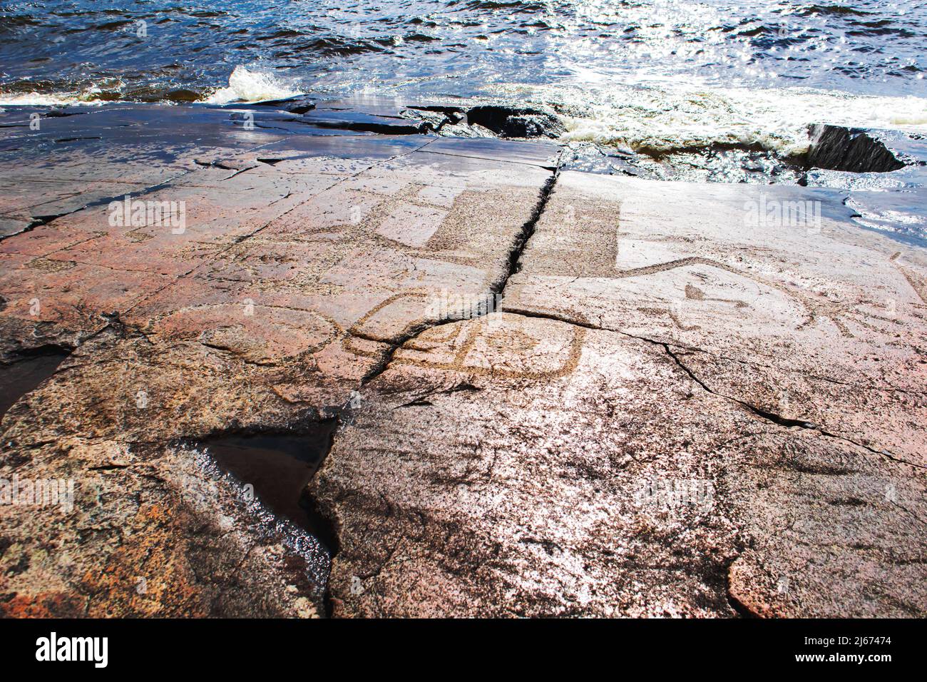Antichi petroglifi sulle rive del Lago Onega. Scolpito su una lastra di granito. Capo Besov Nos, Karelia, Russia - 15 agosto 2021. Foto Stock