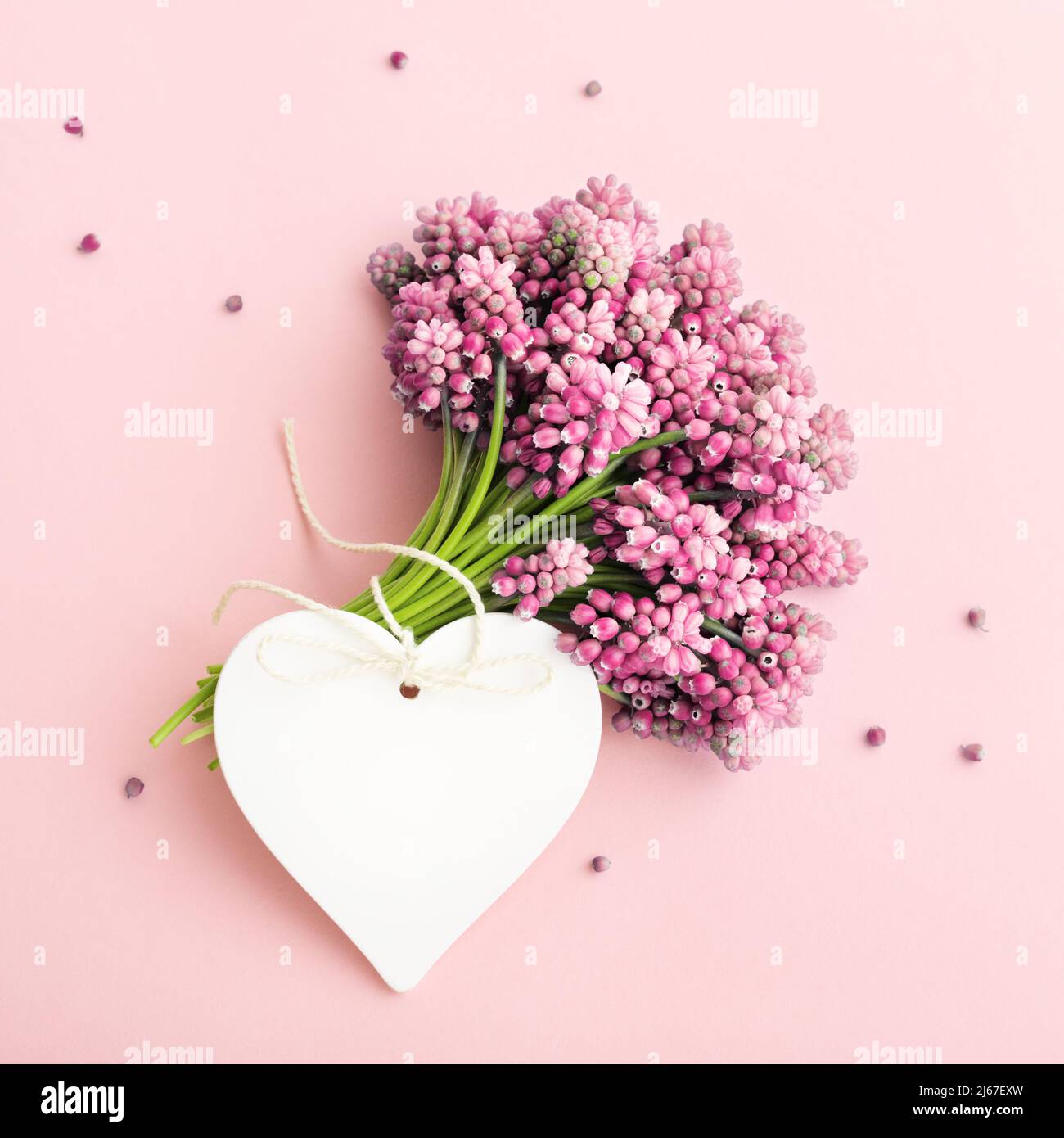 Bouquet di fiori rosa e un biglietto d'auguri a forma di cuore mock up per il giorno della mamma, compleanno, San Valentino, Femminile. Foto Stock