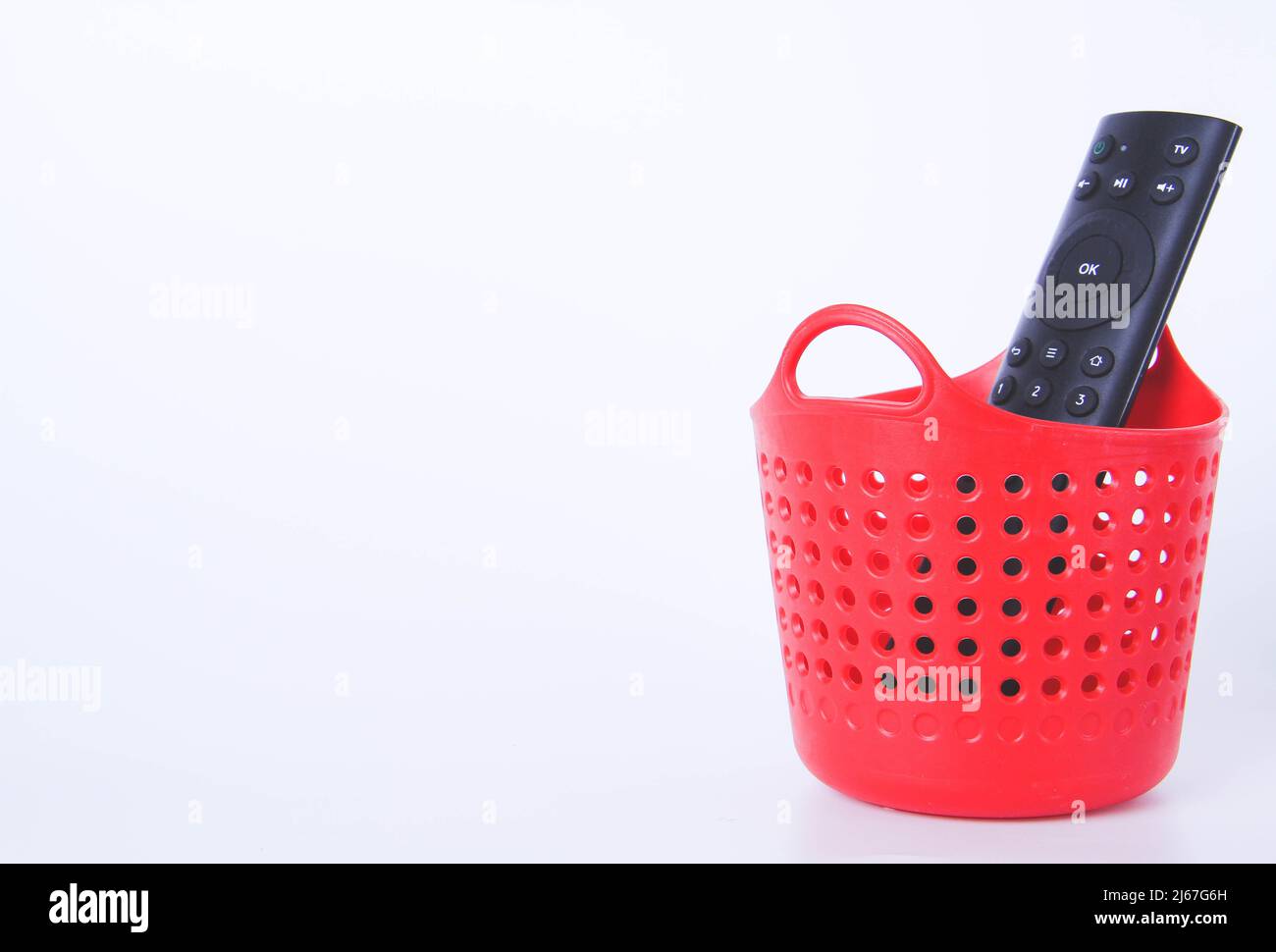 Il telecomando del televisore è nel cestino. Cestino pieno rosso. Smaltimento dei rifiuti domestici. Foto Stock