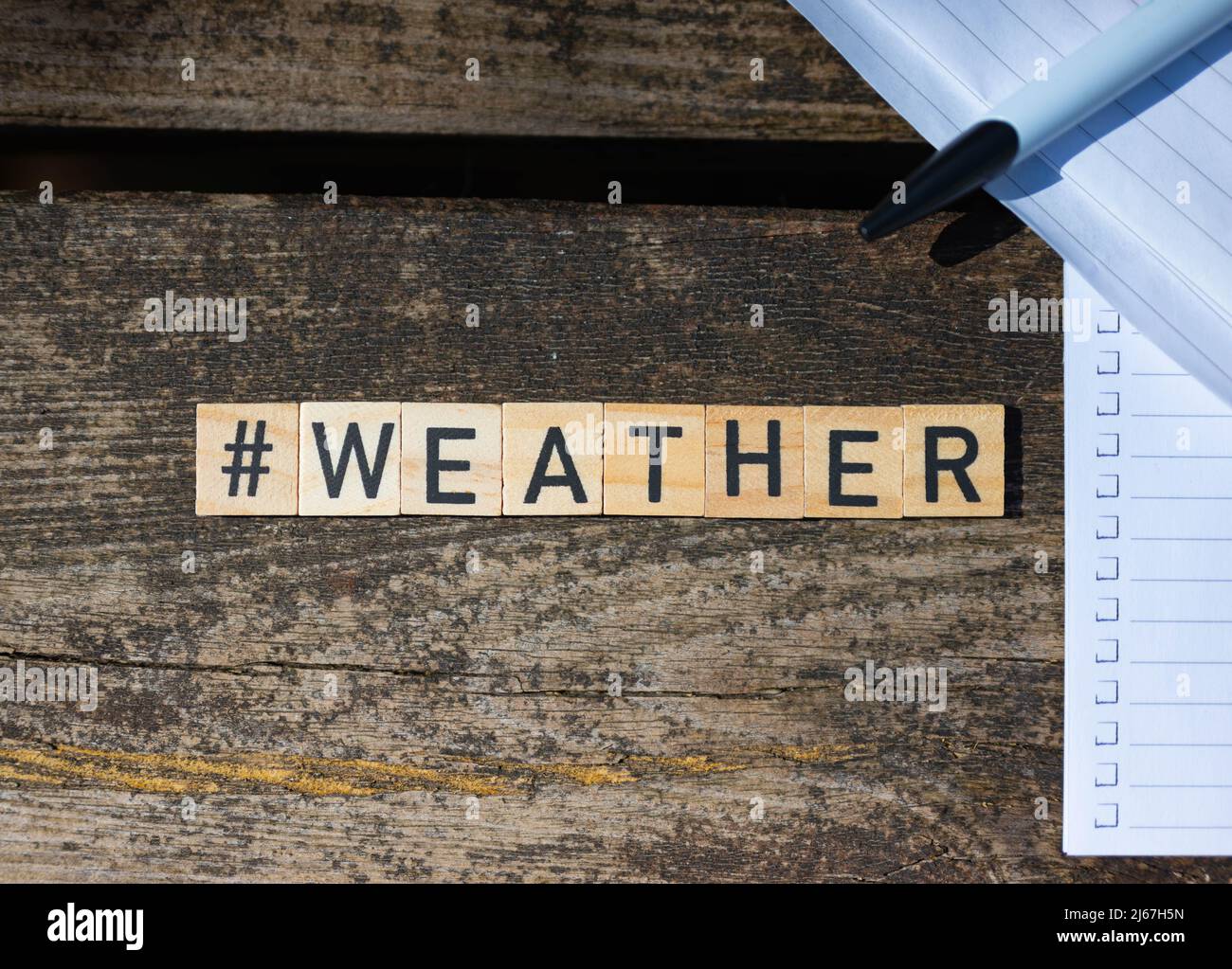 Blocchi giocattolo di legno con il testo meteo su di esso con penna e carta sullo sfondo Foto Stock
