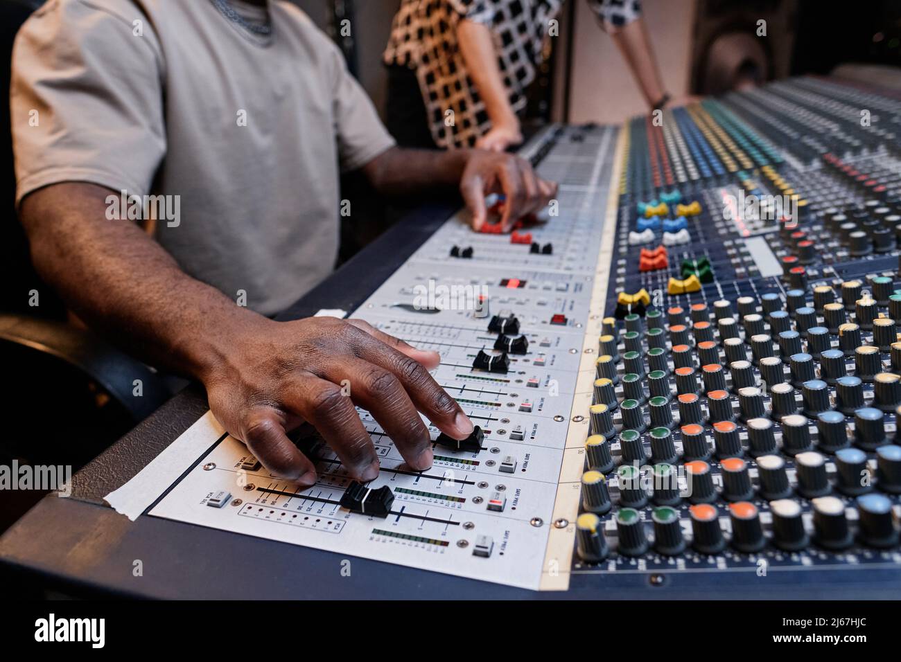Un tecnico audio e un musicista irriconoscibili che creano tracce utilizzando il mixer in studio di registrazione Foto Stock