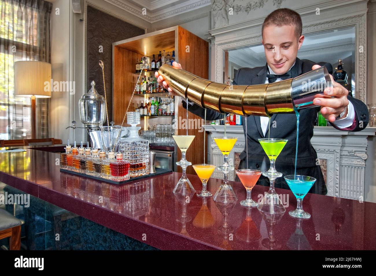 Barista che versa bevande presso un banco bar di un hotel di lusso Foto Stock
