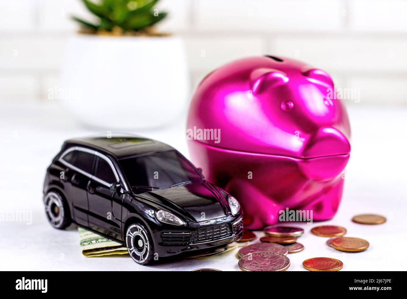 Automobile nera con soldi e banca di moneta del piggy su sfondo chiaro. Assicurazione auto, noleggio e pagamento tasse concetto. Foto Stock