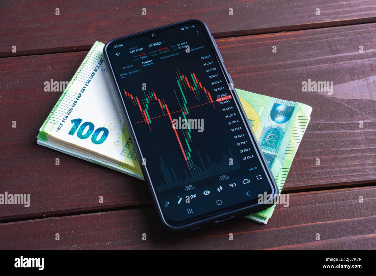 Grafico dei vari tassi di cambio valuta sullo schermo dello smartphone. Gadget intelligente su pila di banconote in euro Foto Stock