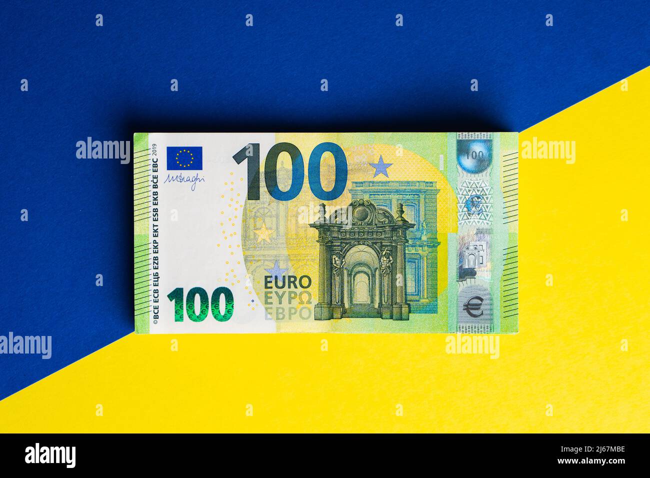 Pila di cento banconote in euro sulla bandiera Ucraina. Aiuti finanziari dall'Europa all'Ucraina concetto Foto Stock