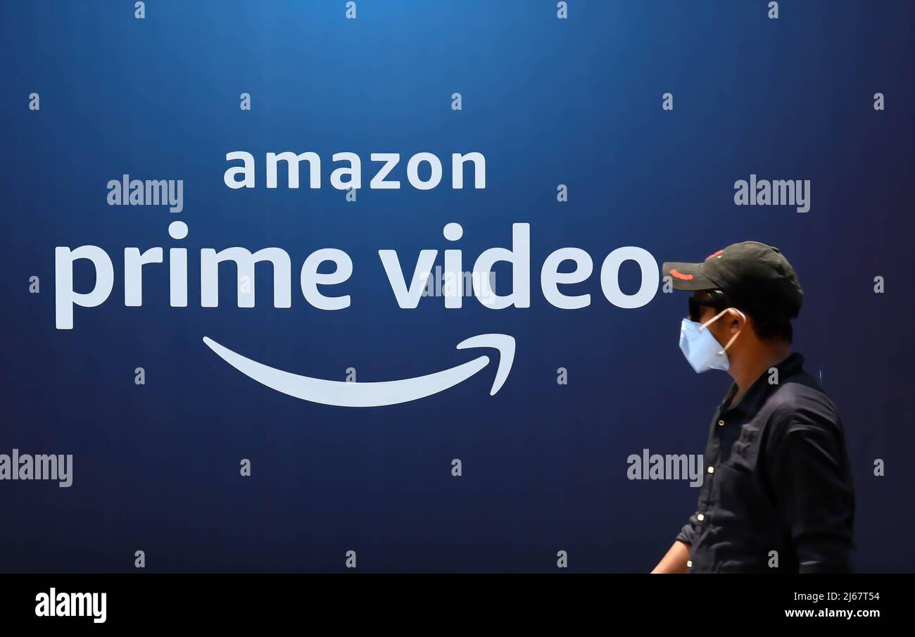 Mumbai, India. 28th Apr 2022. Un uomo che indossa una maschera protettiva passa davanti a un poster del lancio di Amazon prime Video a Mumbai. La società americana di video streaming ha lanciato l'evento per annunciare i suoi piani di investimento per i contenuti in India per i prossimi due anni. Include film e spettacoli in diverse lingue indiane. Credit: SOPA Images Limited/Alamy Live News Foto Stock