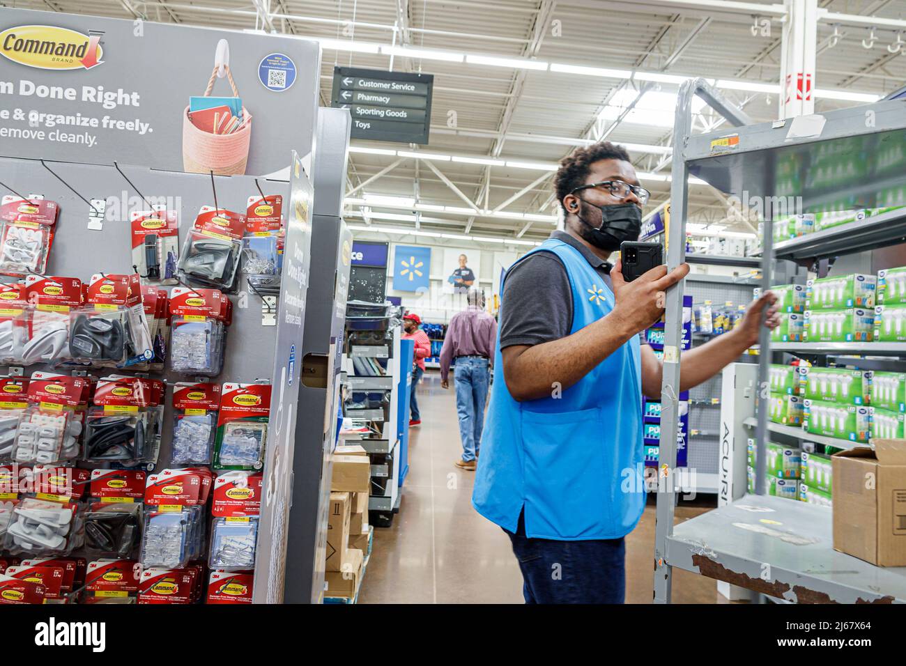 North Miami Beach Florida Walmart discount grande magazzino all'interno shopping interno uomo nero uomo uomo lavoratore dipendente che lavora indossando maschera facciale Covid-19 Foto Stock