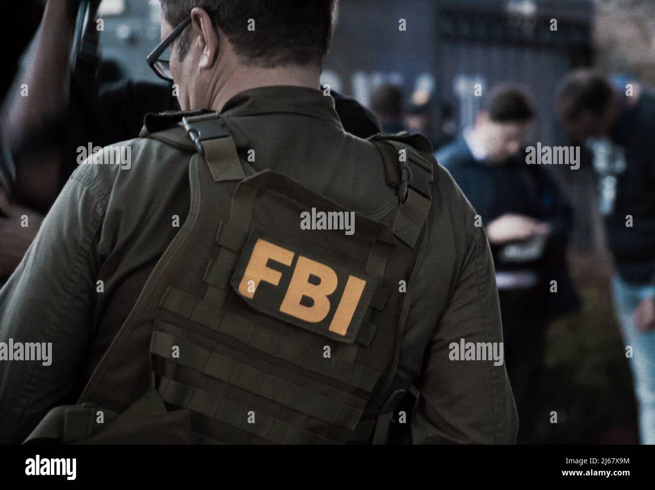 Agente FBI maschio caucasico che indossa occhiali in un gilet verde a prova  di proiettile con logo FBI visto da dietro sul punto di indagine Foto stock  - Alamy