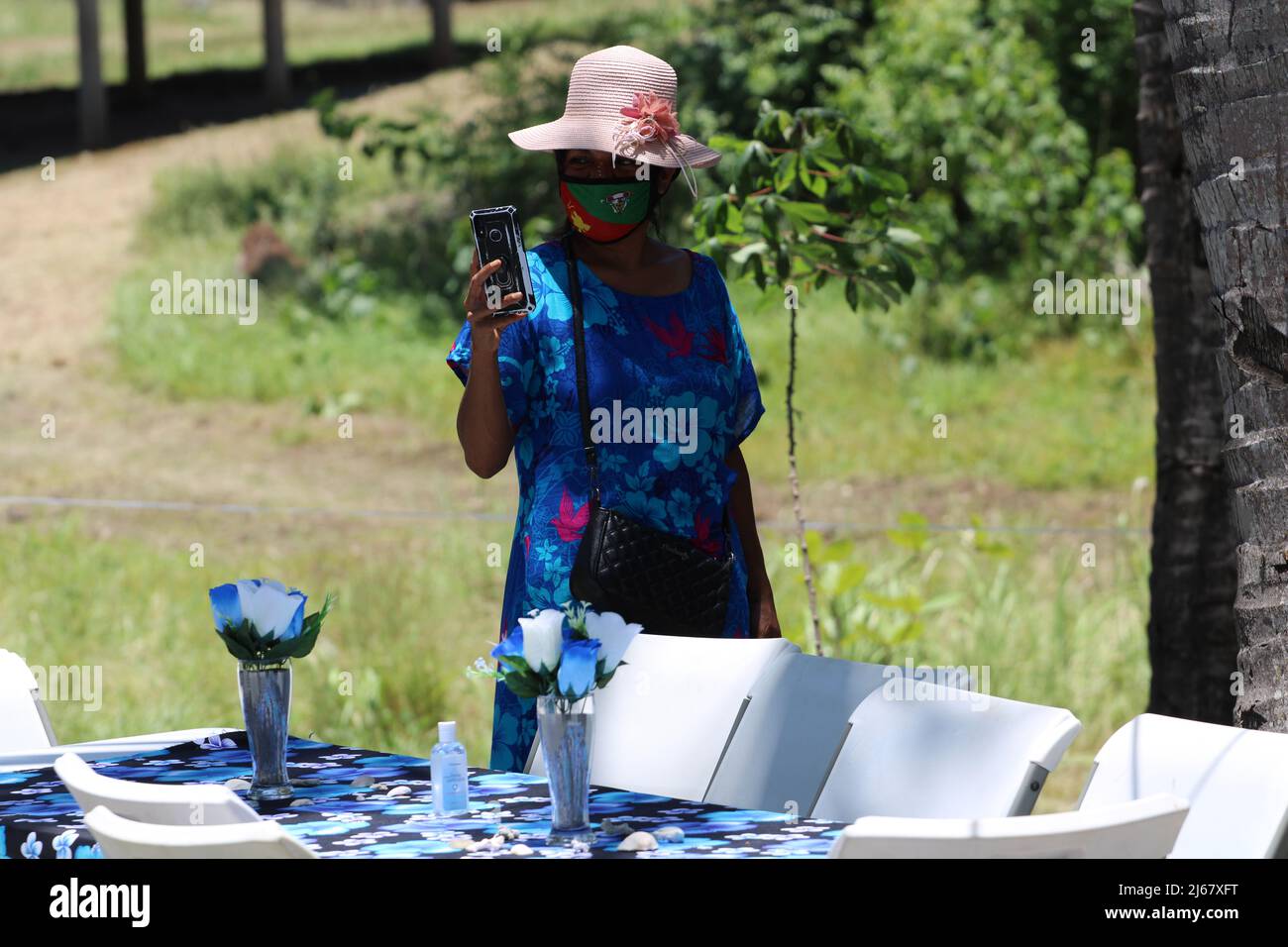Un ospite femminile che fotografa con il suo smartphone in occasione di un matrimonio nel 2021 al villaggio di Papa nella provincia centrale, Papua Nuova Guinea (PNG). Foto Stock