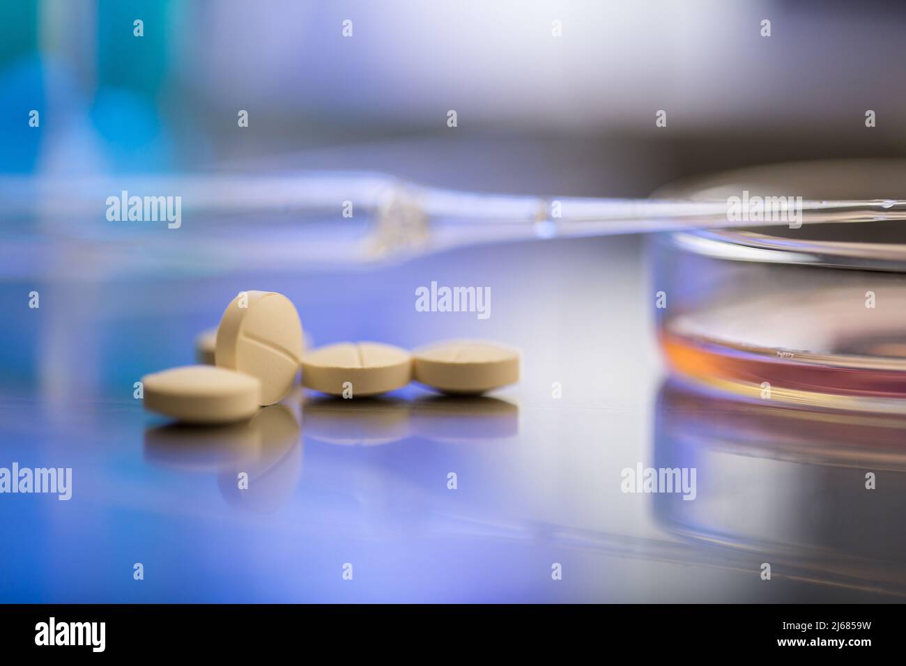 Pillole di colore giallo pallido dal laboratorio con contagocce e piatto di Petri - foto di scorta Foto Stock