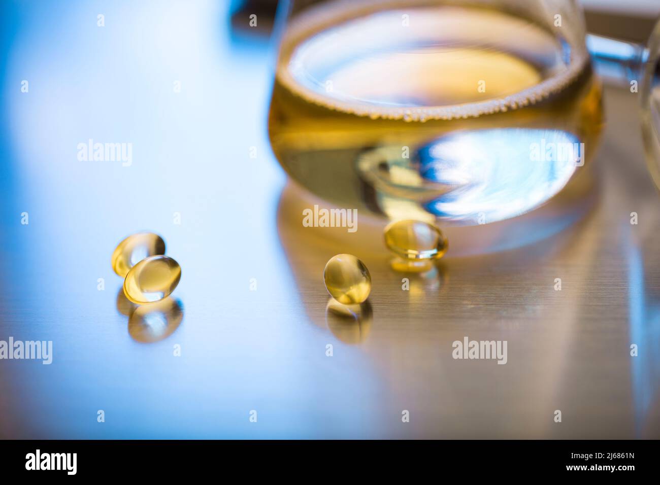 Matraccio conico contenente un medicinale liquido dorato con capsule molli e imbuto - foto di scorta Foto Stock