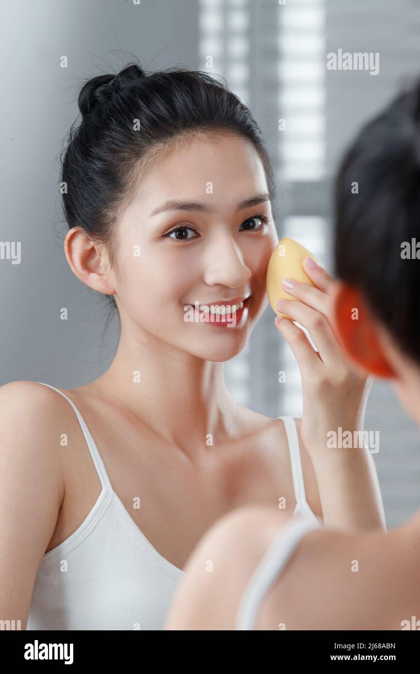 La giovane donna nello specchio trucco Foto Stock