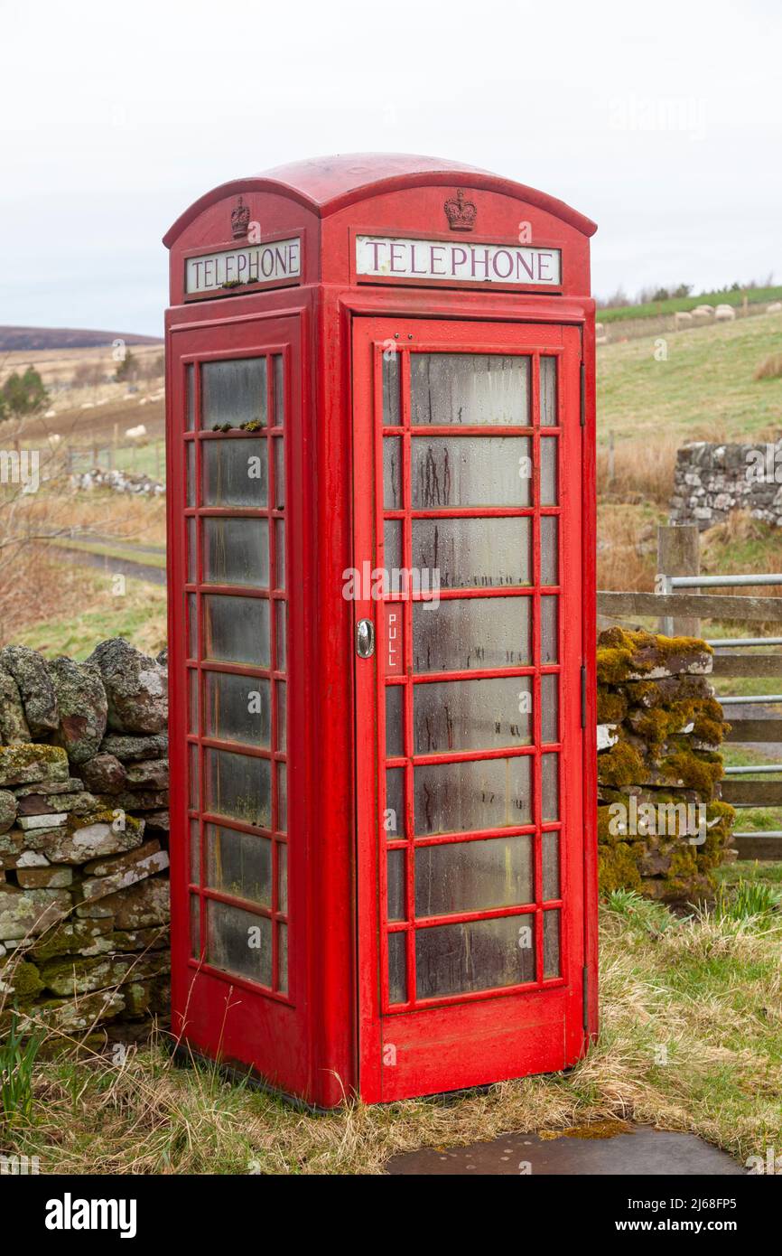 Un vecchio telefono rosso britannico in un ambiente rurale Foto Stock