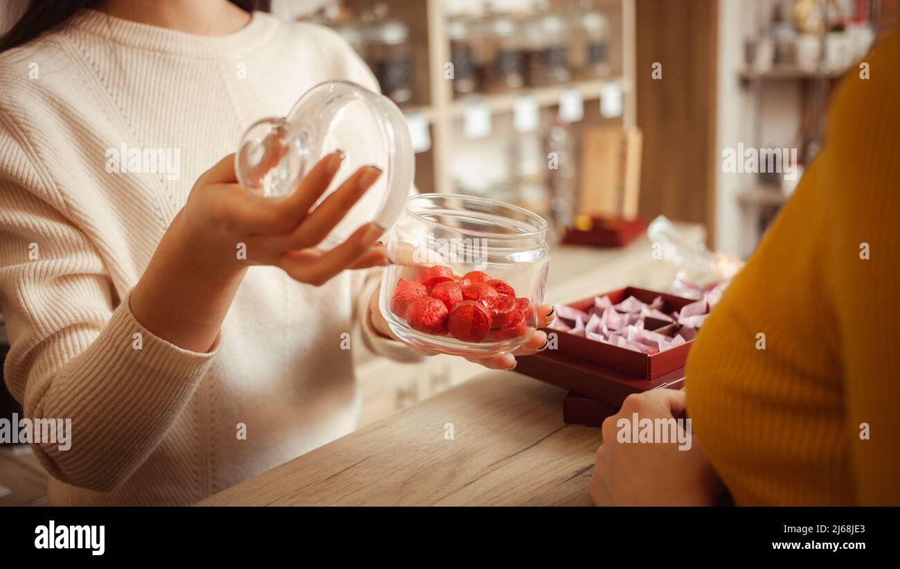 Donna sceglie regalo per San Valentino, bel tè in confezione rossa. Negozio di tè, il venditore offre prodotti. tè in pacchetto Foto Stock