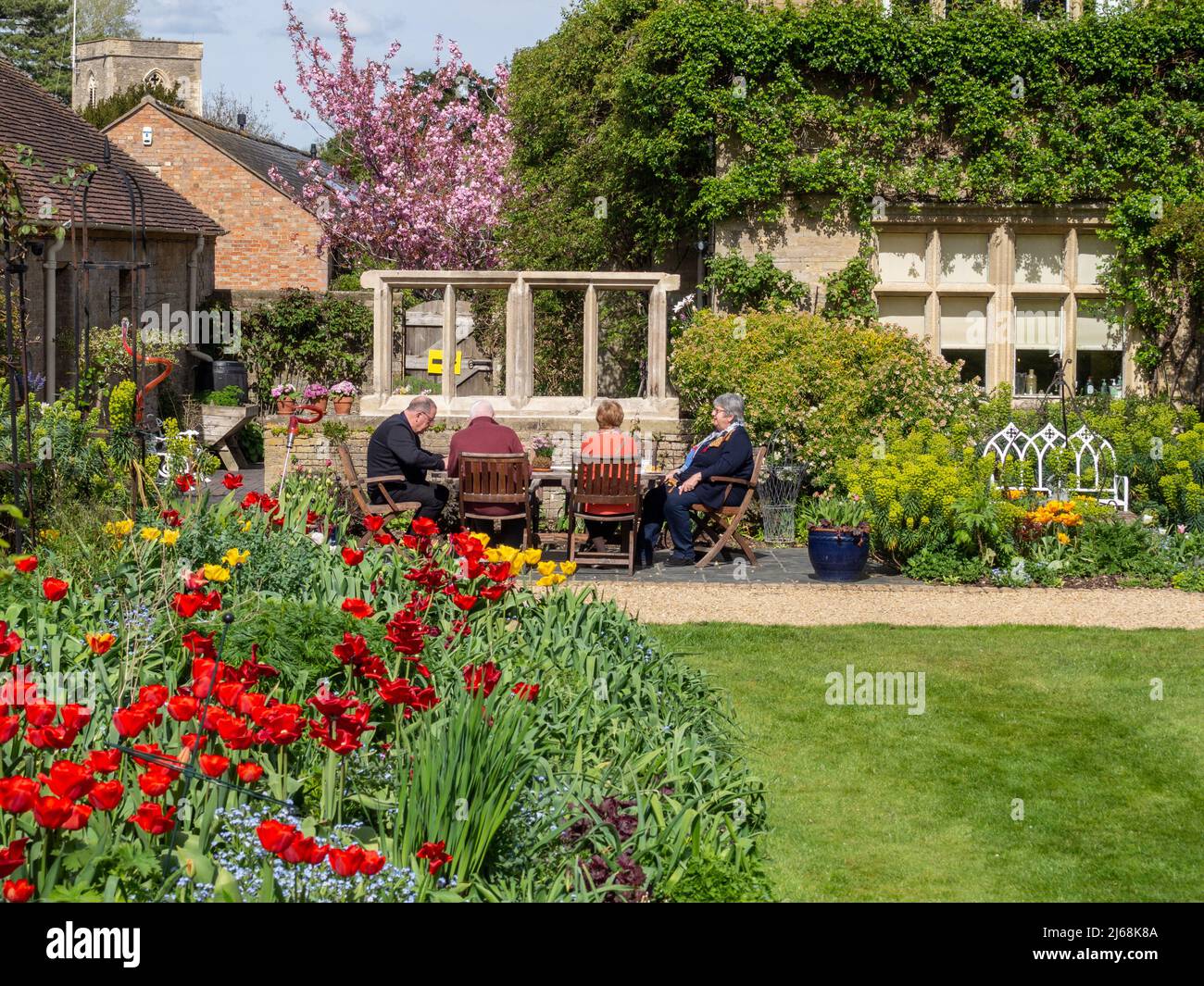 I visitatori potranno gustare il tè pomeridiano in una calda giornata di sole primaverile, il giardino di Kathy Brown, Stevington, Bedfordshire, Regno Unito Foto Stock