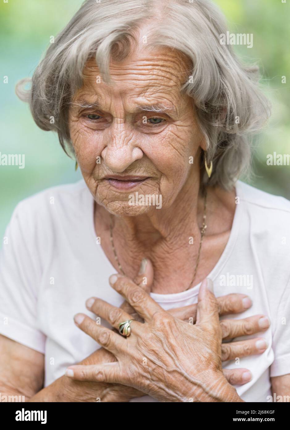 Donna anziana all'aperto con dolore al cuore che tiene il suo petto Foto Stock