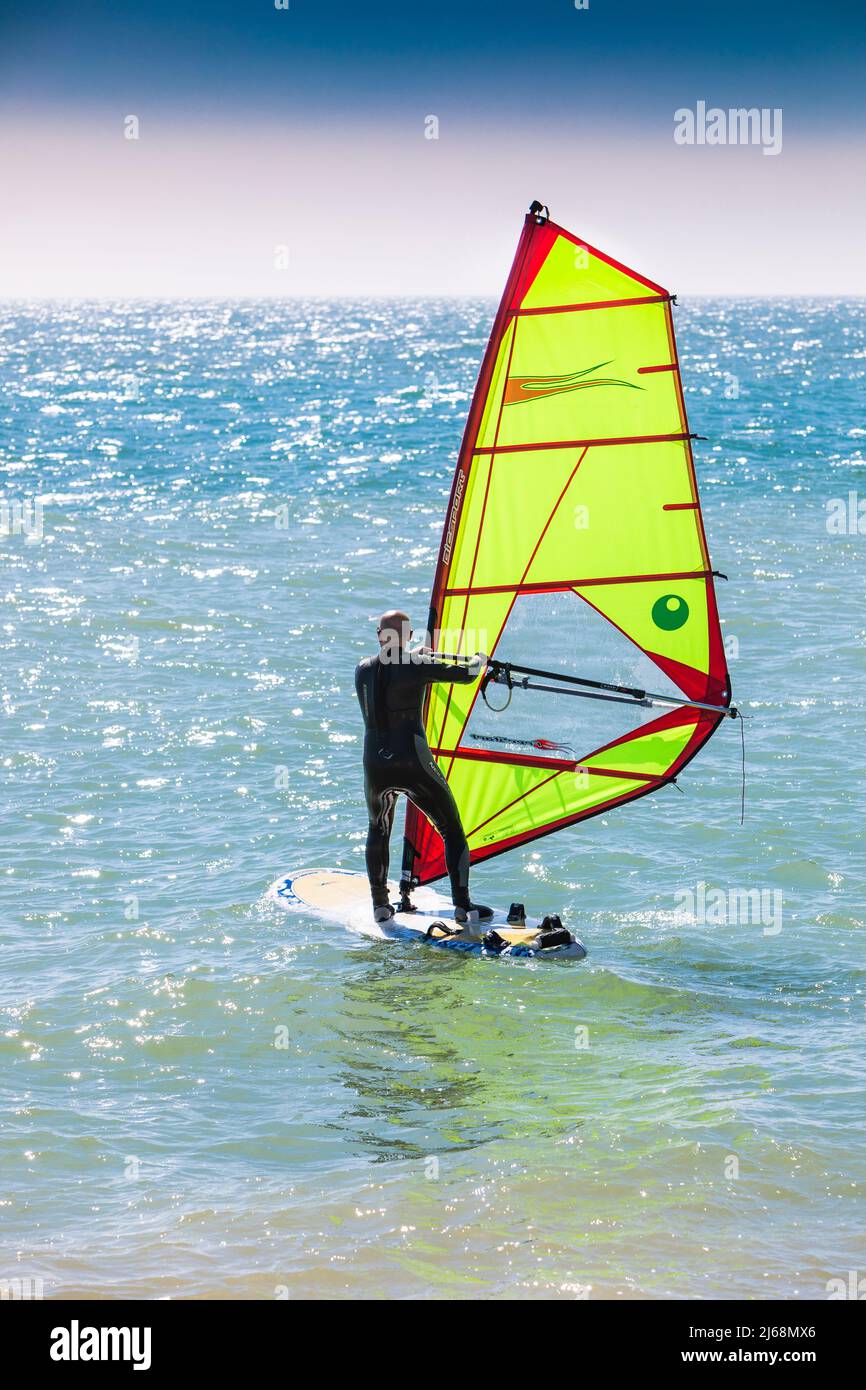 Un surfista del vento con una vela verde calce brillante Foto Stock