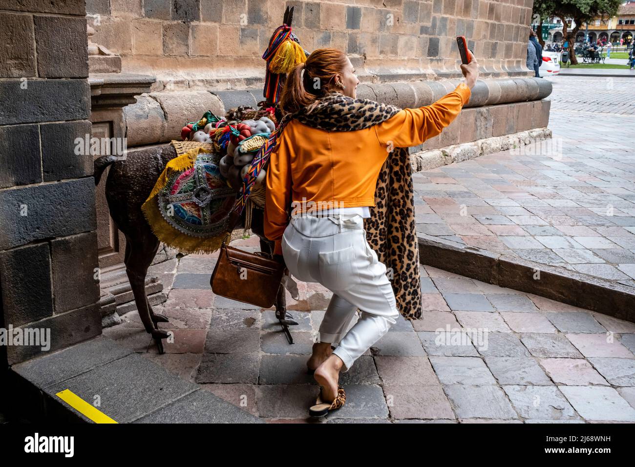 Una giovane donna che prende un selfie nella Plaza De Armas con Un modello Llama , Cusco, Provincia di Cusco, Perù. Foto Stock