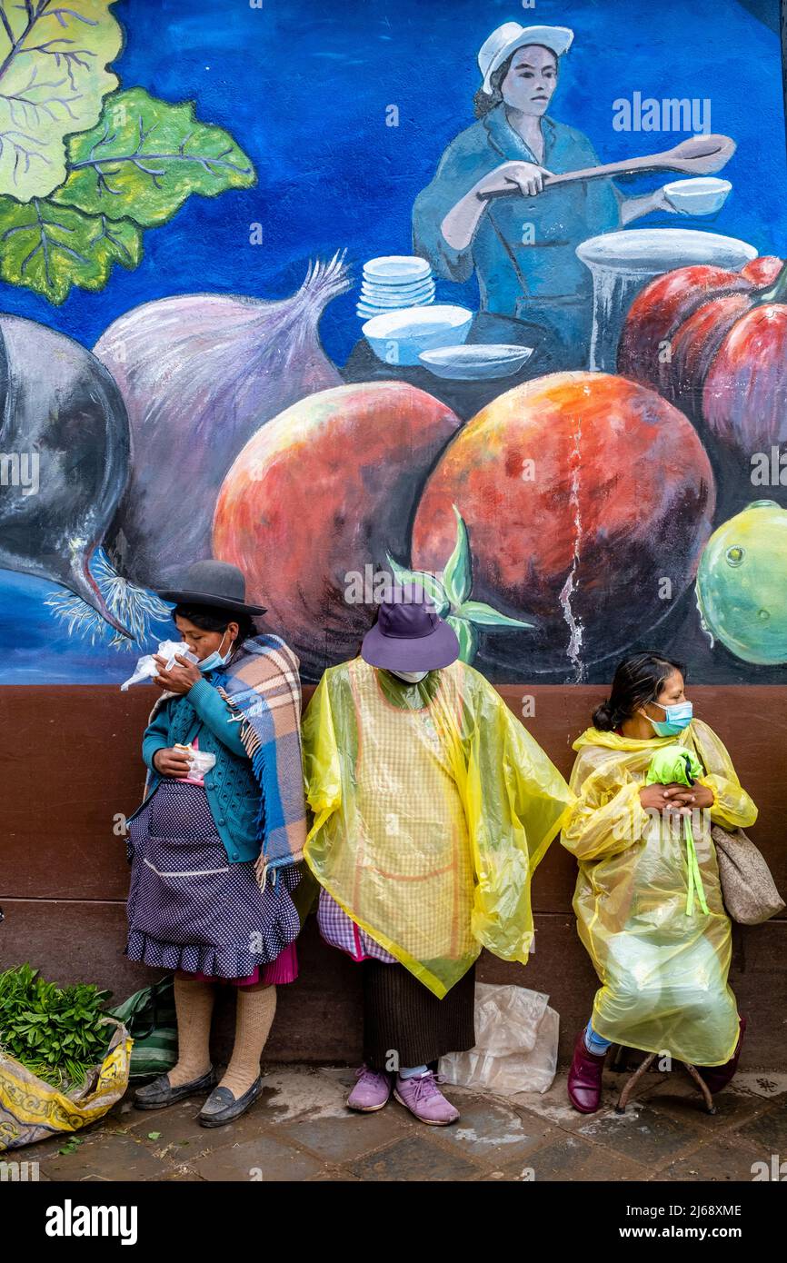Un piccolo gruppo di donne peruviane in piedi in strada durante Una doccia a pioggia, Cusco, Provincia di Cusco, Perù. Foto Stock