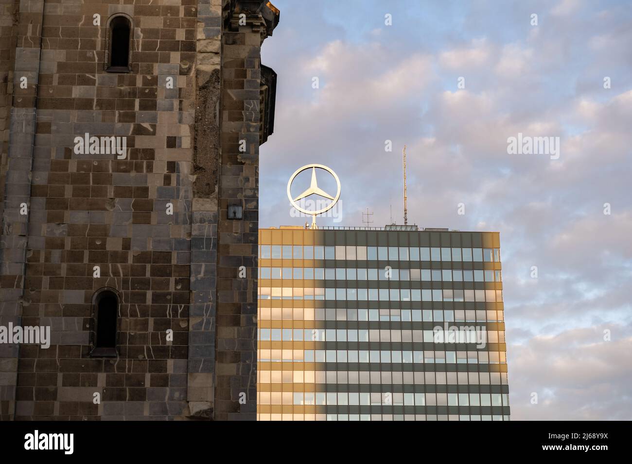 Gruppo Mercedes-Benz nella capitale della Germania. Emblema che gira sul tetto di un alto edificio come una grande pubblicità nello skyline del tramonto. Foto Stock