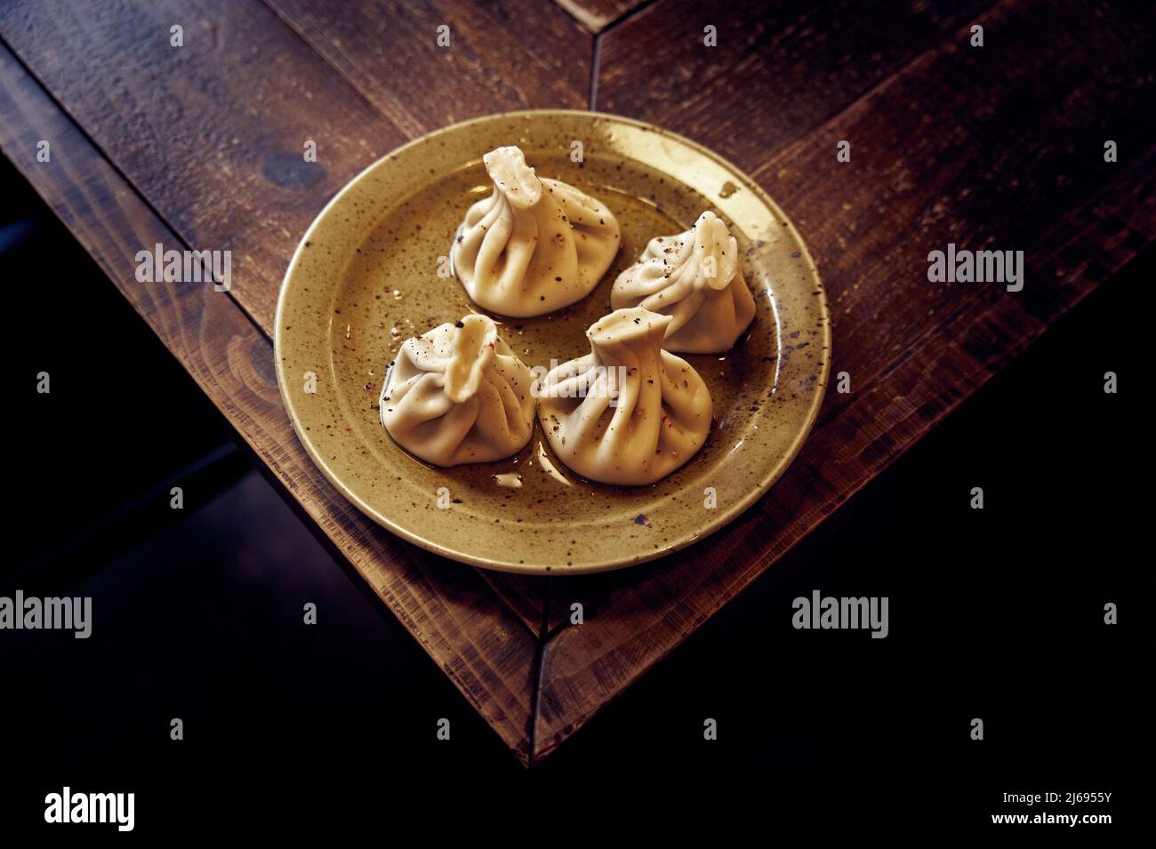 Cucina georgiana. Appetitoso khinkali di carne di agnello in un piatto di ceramica su un tavolo di legno Foto Stock