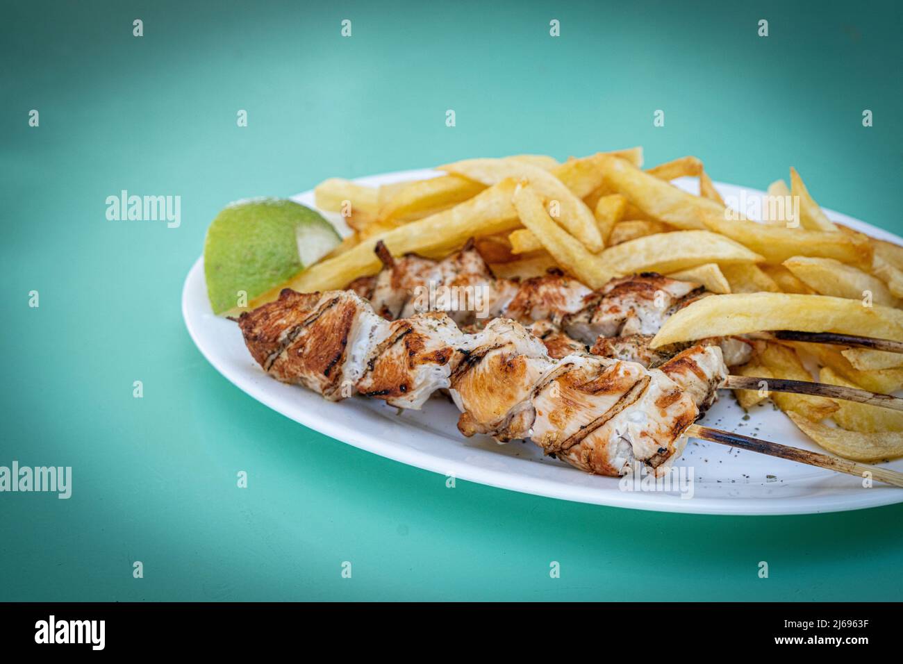 Souvlaki, popolare cibo greco costituito da piccoli pezzi di carne alla griglia su uno spiedino servito con patatine fritte, Isole greche, Grecia, Europa Foto Stock