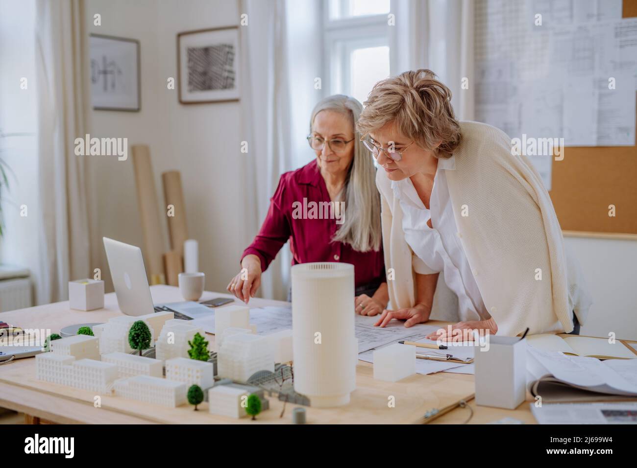 Le donne mature eco architetti con modello di moderni bulidings e progetti che lavorano insieme in ufficio. Foto Stock