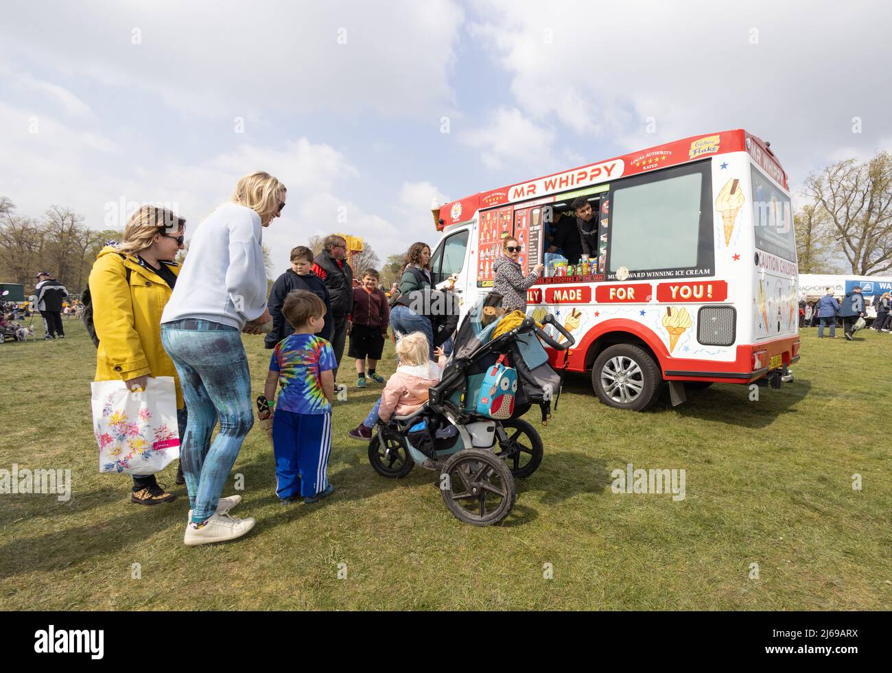 Ice cream van UK; una famiglia con bambini in fila per acquistare gelato da un uomo MR Whippy Ice Cream, in una giornata di sole in primavera, Suffolk UK Foto Stock