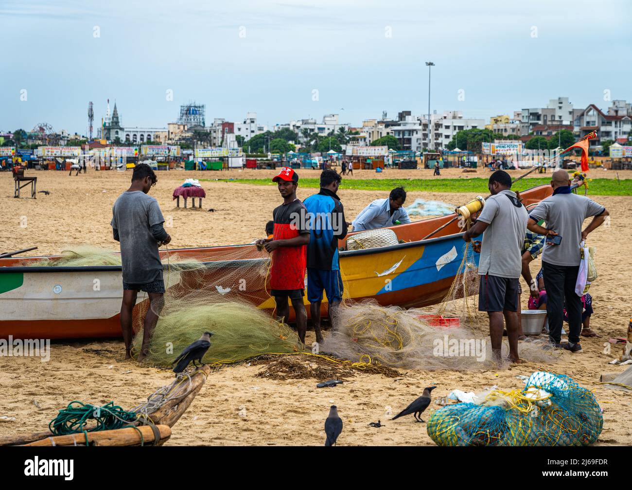 Un gruppo di giovani pescatori maschi adulti che preparano le reti da pesca alla spiaggia di Edward Elliot a Besant Nagar. Foto Stock